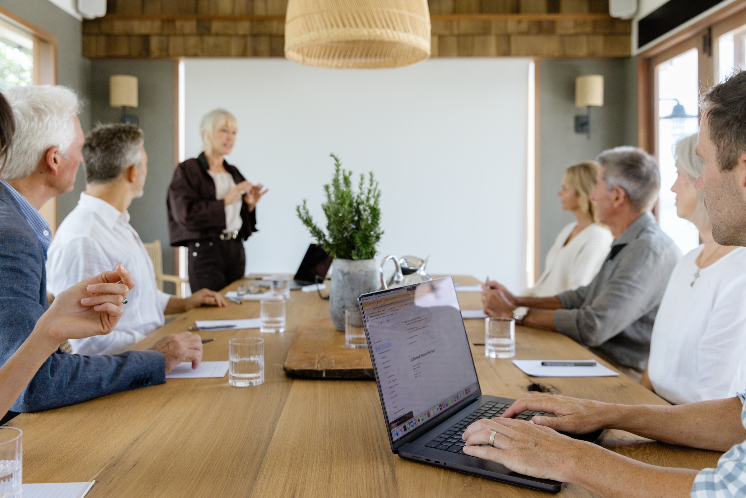 A presenter speaking to a table of executives at the Cookhouse, Bluestone Ridge, laptops open, the screen blank behind her.